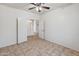 An inviting bedroom featuring double doors, a ceiling fan, and neutral tile flooring at 15985 W Bartlett Ave, Goodyear, AZ 85338