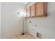 Compact laundry room with essential hookups and convenient storage above, illuminated by a modern lamp at 15985 W Bartlett Ave, Goodyear, AZ 85338