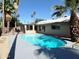 Backyard with an inviting pool surrounded by a gray concrete deck and lush palm trees on a sunny day at 1712 E Manhatton Dr, Tempe, AZ 85282