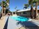 Sunlit backyard features a sparkling pool, patio area, palm trees, and partial view of the house at 1712 E Manhatton Dr, Tempe, AZ 85282