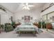 Spacious bedroom with vaulted ceiling, ceiling fan, bedside tables, sitting chair and sliding mirror closet at 17543 N Rainbow Cir, Surprise, AZ 85374