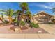 Charming single-story home with desert landscaping, palm trees, and a two-car garage at 17543 N Rainbow Cir, Surprise, AZ 85374