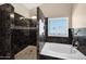 The bathroom features a luxurious black tiled shower and a soaking tub with natural light at 1755 N 74 Th Pl, Mesa, AZ 85207