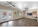 Bright living room with wood floors, ceiling fans, backyard access, and mounted TV at 1755 N 74Th Pl, Mesa, AZ 85207