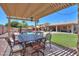 Inviting outdoor dining area beneath a pergola, overlooking a lush lawn, waterfall feature, and beautiful home at 2041 E Palm Beach Dr, Chandler, AZ 85249