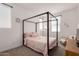 This bedroom features a black canopy bed with pink bedding and a sitting chair near a sunny window at 22682 E Indiana Ave, Queen Creek, AZ 85142