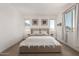 Cozy bedroom with a comfortable bed, side tables, two windows with natural light, and carpet flooring at 22682 E Indiana Ave, Queen Creek, AZ 85142