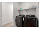 This bright laundry room features a stacked washer and dryer, and ample storage on the floating shelves above at 22682 E Indiana Ave, Queen Creek, AZ 85142