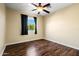 Bright bedroom featuring a ceiling fan, wood-look floors, and a window with black curtains at 24645 N 65Th Ave, Glendale, AZ 85310