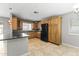 Well-equipped kitchen featuring wood cabinetry, black appliances, granite countertops, and tile flooring, providing a functional design at 2633 E Garnet Ave, Mesa, AZ 85204