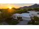 Aerial view of home showcasing modern architecture, lush greenery, mountain views, and a warm sunset glow at 3186 E Stella Ln, Phoenix, AZ 85016