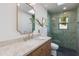 Well-lit bathroom featuring a stylish vanity, a sink, and a shower with green tiling at 3186 E Stella Ln, Phoenix, AZ 85016