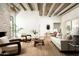 The open living room boasts a stone fireplace, beamed ceilings, wood floors and neutral-toned furniture at 3186 E Stella Ln, Phoenix, AZ 85016