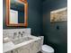 Modern powder room featuring a unique marble sink, custom mirror, and dark green walls at 3186 E Stella Ln, Phoenix, AZ 85016