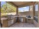 Covered outdoor kitchen featuring a grill, cooking space, mini fridge and desert landscaping at 3859 N El Sereno St, Mesa, AZ 85207
