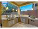 Outdoor kitchen with stainless steel grill, mini fridge, and travertine tile under hanging pendant lights at 3859 N El Sereno St, Mesa, AZ 85207