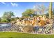 Artificial water feature cascading over rocks with desert vegetation and blue sky background at 3859 N El Sereno St, Mesa, AZ 85207