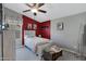 Cozy bedroom with red accent wall, ceiling fan, and vintage-inspired decor at 41465 W Sussex Dr, Maricopa, AZ 85138