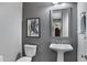Elegant powder room featuring a pedestal sink, stylish mirror, and decorative artwork, creating a sophisticated ambiance at 41465 W Sussex Dr, Maricopa, AZ 85138