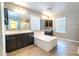 Bathroom showcasing an expansive bathtub, dual vanities with dark cabinetry, and neutral tile flooring at 4277 N 180Th Ln, Goodyear, AZ 85395