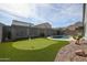 Private backyard with putting green, pool, desert landscaping, and block wall fencing at 4593 W Bush Bean Way, San Tan Valley, AZ 85144