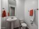 A modern powder room featuring a pedestal sink, a toilet, a mirror and chrome hardware at 4593 W Bush Bean Way, San Tan Valley, AZ 85144