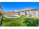 Beautiful backyard featuring a private pool, lush artificial turf, and covered patio area at 709 E Dry Creek Rd, San Tan Valley, AZ 85143