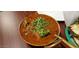 Top-down view of curry dish topped with greens in a silver bowl, accompanied by naan bread at 742 E Kyle Dr, Gilbert, AZ 85296
