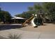 Community playground with slides and covered picnic area, set against a backdrop of mature trees and residential buildings at 8920 S 40Th Ln, Laveen, AZ 85339