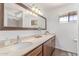 Bright bathroom showcasing a large mirror, double sinks, wood cabinets, and modern lighting at 9623 N 34Th Pl, Phoenix, AZ 85028