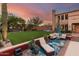 A beautiful backyard with outdoor lounge, lush green grass, mature trees, basketball court, and patio for relaxation and entertainment at 9753 E Suncrest Rd, Scottsdale, AZ 85262