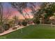 A lovely backyard with a putting green, mature trees, desert landscaping, and relaxing bench seating at 9753 E Suncrest Rd, Scottsdale, AZ 85262
