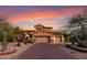 Elegant two-story home with a three-car garage, desert landscaping, and a paver driveway at sunset at 9753 E Suncrest Rd, Scottsdale, AZ 85262