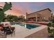 A gorgeous pool with a spa and adjacent covered patio with a backdrop of a home at dusk at 9753 E Suncrest Rd, Scottsdale, AZ 85262