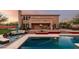 A stunning pool featuring comfortable seating areas and lush desert landscaping, set against a backdrop of a two-story house at 9753 E Suncrest Rd, Scottsdale, AZ 85262