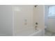 Bathroom featuring a bathtub with shower, tiled walls, and a window for natural light, creating a clean and refreshing space at 1031 W Longhorn Dr, Chandler, AZ 85286