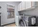 Laundry room featuring a front-load washer and dryer, overhead storage, and a window at 1231 W Mediterranean Dr, Gilbert, AZ 85233