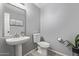 Powder room with pedestal sink, toilet, modern mirror, and decor at 1231 W Mediterranean Dr, Gilbert, AZ 85233