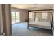 This bedroom with neutral carpet features a modern four-poster bed and access to the outdoor balcony at 14021 N 29Th St, Phoenix, AZ 85032