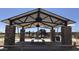 A covered pavilion in a park, featuring stone columns, picnic tables, and playground equipment in the background at 14385 W Sand Hills Rd, Surprise, AZ 85387