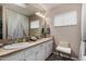 Bright bathroom featuring dual sinks, white cabinets, a large mirror, and a window at 2319 N 58Th St, Scottsdale, AZ 85257