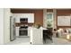 Stylish kitchen with stainless steel appliances, white cabinets, island with seating, and adjacent living area at 23361 W Atlanta Ave, Buckeye, AZ 85326