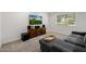 Comfortable living room includes a gray sofa, wooden cabinet, plush ottoman, and neutral decor at 2350 E Melrose St, Gilbert, AZ 85297