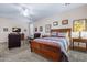 Bright bedroom showcases a decorative wood bed frame, ceiling fan, neutral paint and carpeted floors at 2422 W Maya Way, Phoenix, AZ 85085