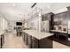 Spacious kitchen overlooking the living room featuring dark cabinets, stainless steel appliances, and a granite island at 2460 E Crescent Way, Gilbert, AZ 85298