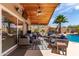 Covered patio with cozy seating, ceiling fan, and views of the sparkling pool and lush backyard at 24813 N 55Th Dr, Glendale, AZ 85310