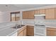 Kitchen area featuring an open layout, wooden cabinets, white appliances, and stainless steel sink at 330 S Valley Dr, Apache Junction, AZ 85120