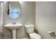 Powder room with pedestal sink, round mirror, and neutral wall color scheme at 4242 E Erie St, Gilbert, AZ 85295