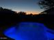 A beautiful dark blue inground pool at dusk with a dark outline of the landscape and homes in the distance at 4554 E Coyote Wash Dr, Cave Creek, AZ 85331