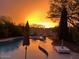A beautiful pool on a patio with an outdoor seating area with a vibrant orange sunset at 4554 E Coyote Wash Dr, Cave Creek, AZ 85331